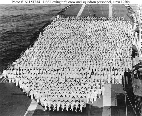 Ship"s crew and personnel of her aircraft squadrons posed on the flight deck, circa the 1930s.