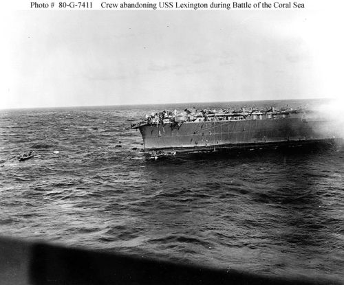 Crewmen sliding down lines at the stern of USS "Lexington" (CV-2), as the carrier is abandoned 
during the afternoon of 8 May 1942